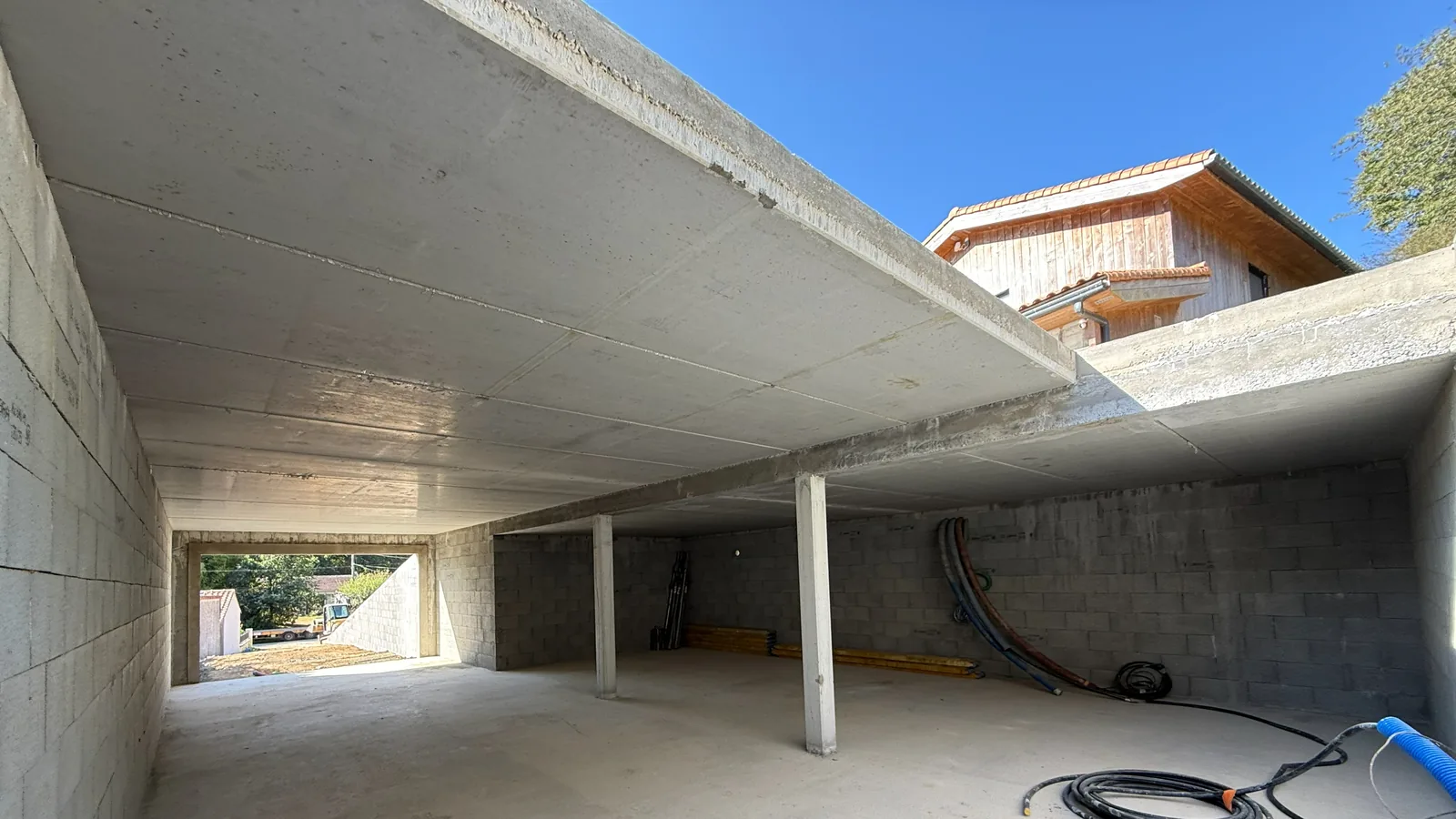 Dalle en béton armé coulée sur un chantier de gros œuvre, vue depuis le sous-sol, maison voisine en arrière-plan